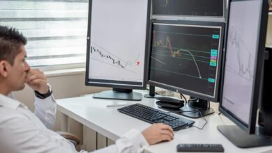 Multiple computer monitors displaying financial trading data and market charts in a modern trading environment