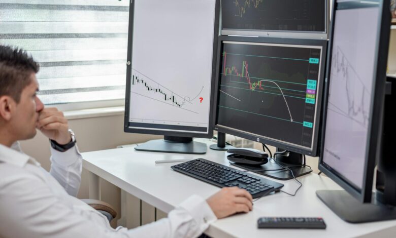 Multiple computer monitors displaying financial trading data and market charts in a modern trading environment