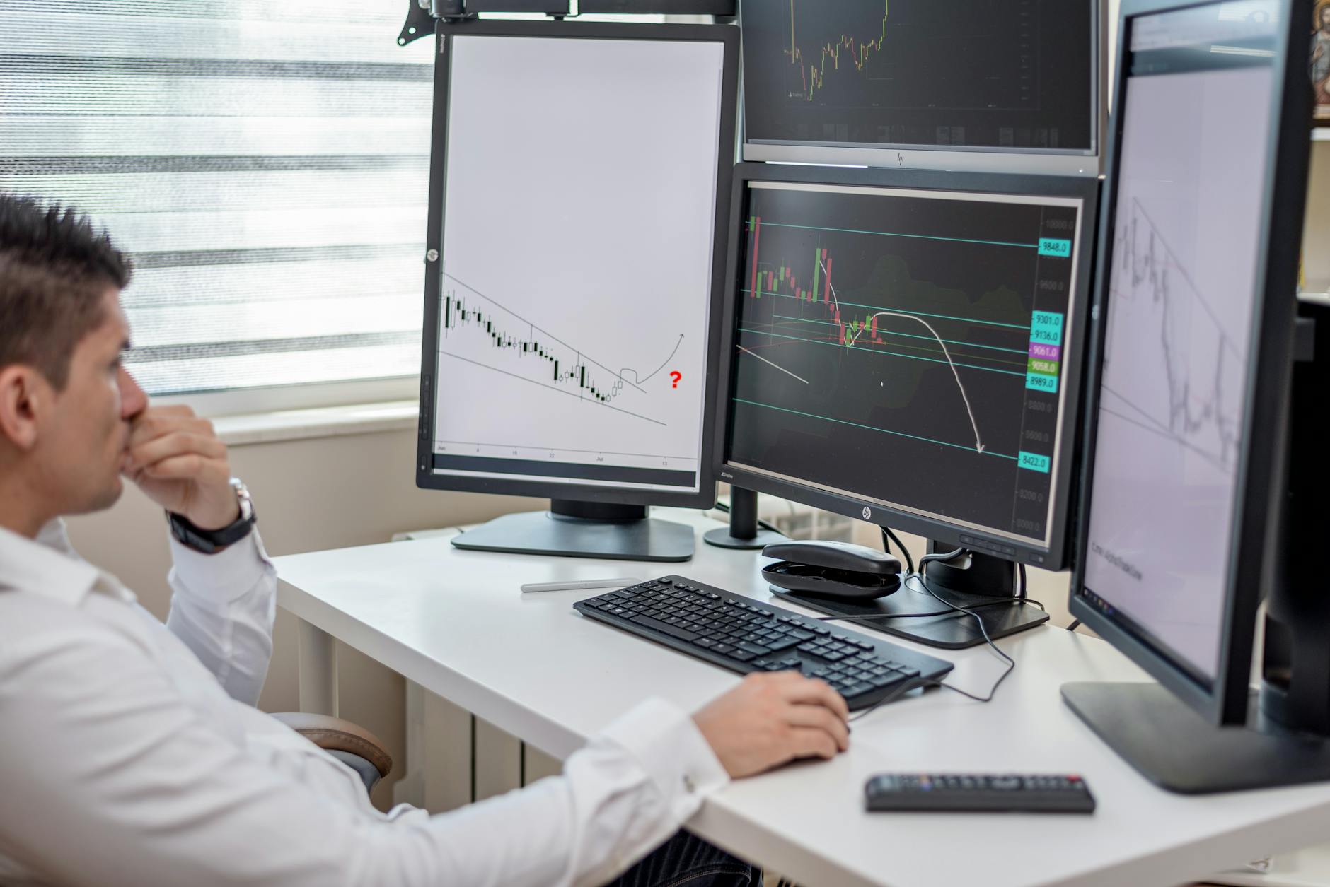 Multiple computer monitors displaying financial trading data and market charts in a modern trading environment