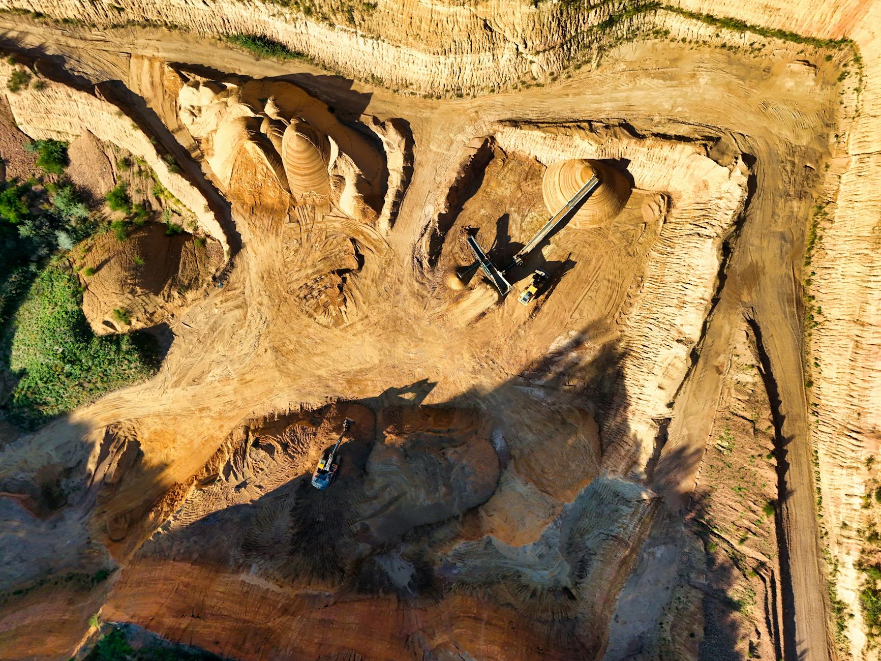 Heavy mining equipment operating in an open-pit mining site with rocky terrain