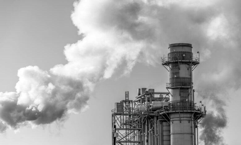 Industrial power plant with steam rising from cooling towers against blue sky