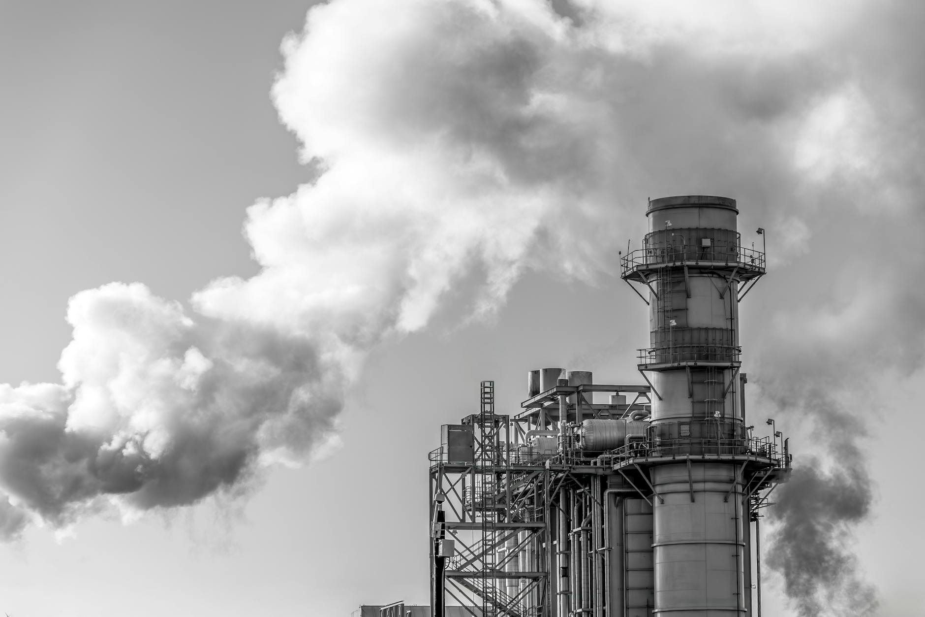Industrial power plant with steam rising from cooling towers against blue sky
