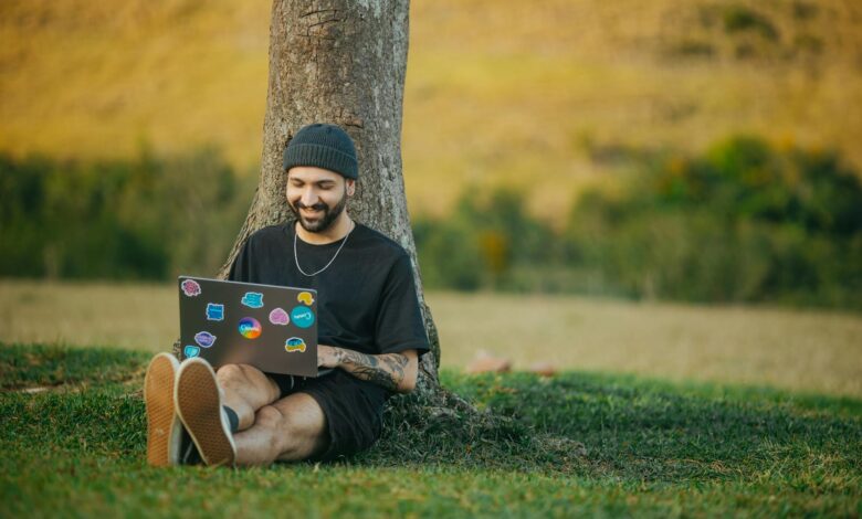 Person working on laptop computer in rural countryside setting with farmland in background