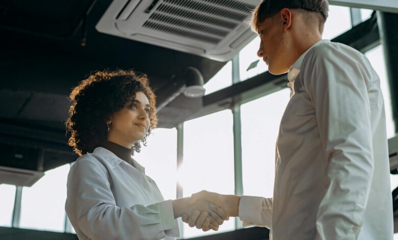 Business professionals shaking hands across desk in modern office setting
