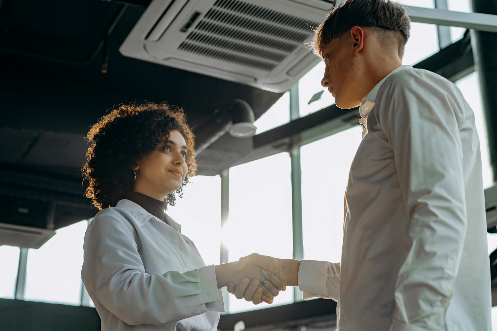 Business professionals shaking hands across desk in modern office setting