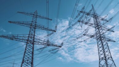 High-voltage electrical transmission towers against cloudy sky representing grid infrastructure
