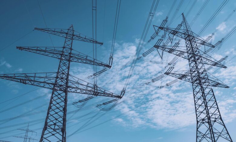 High-voltage electrical transmission towers against cloudy sky representing grid infrastructure