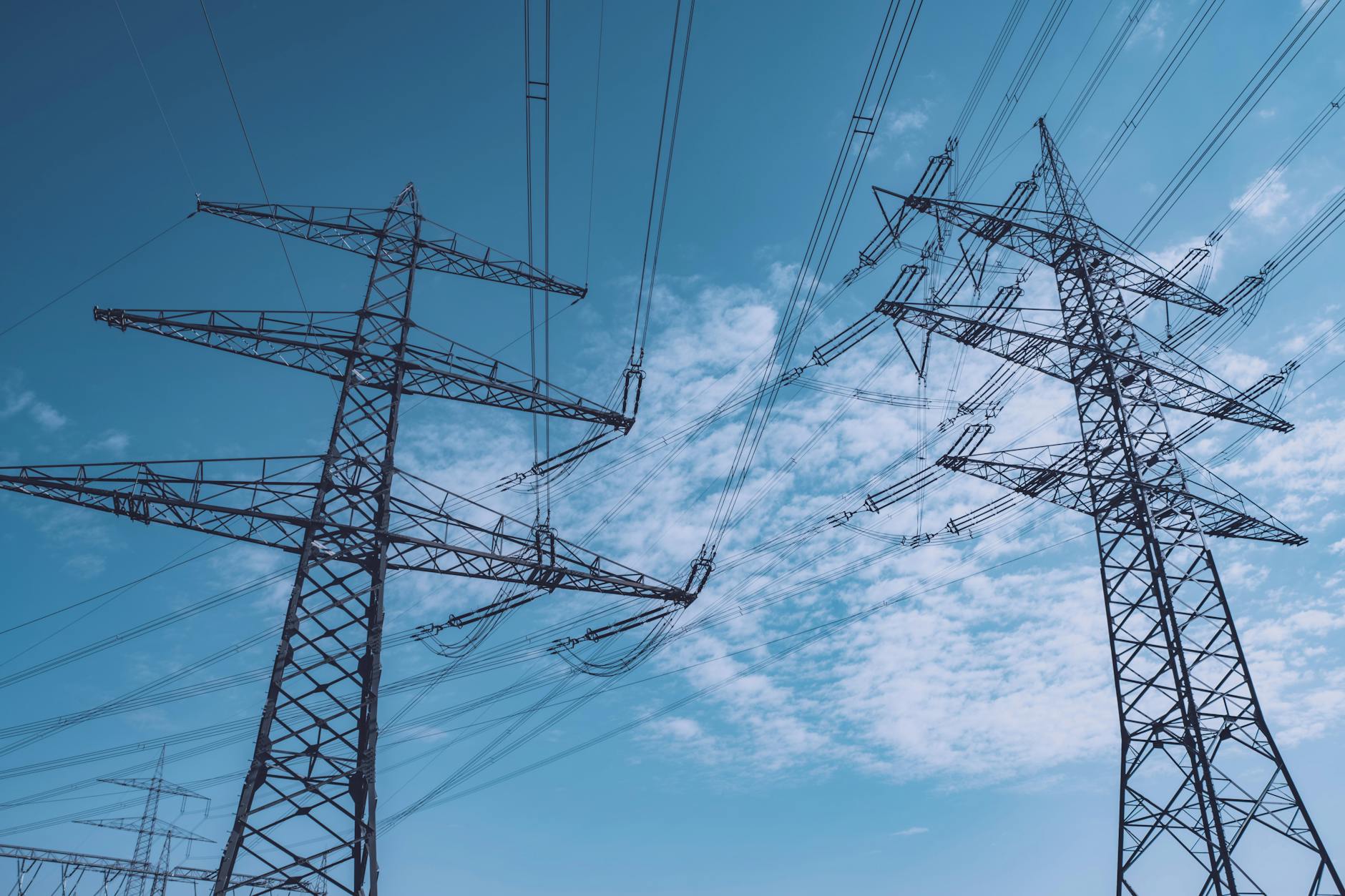 High-voltage electrical transmission towers against cloudy sky representing grid infrastructure