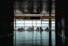 Travelers walking through busy airport terminal with luggage and departure boards