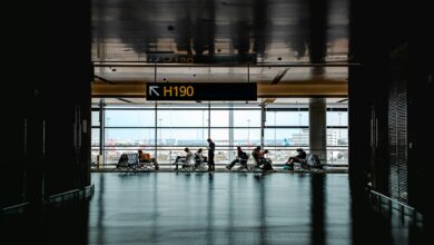 Travelers walking through busy airport terminal with luggage and departure boards