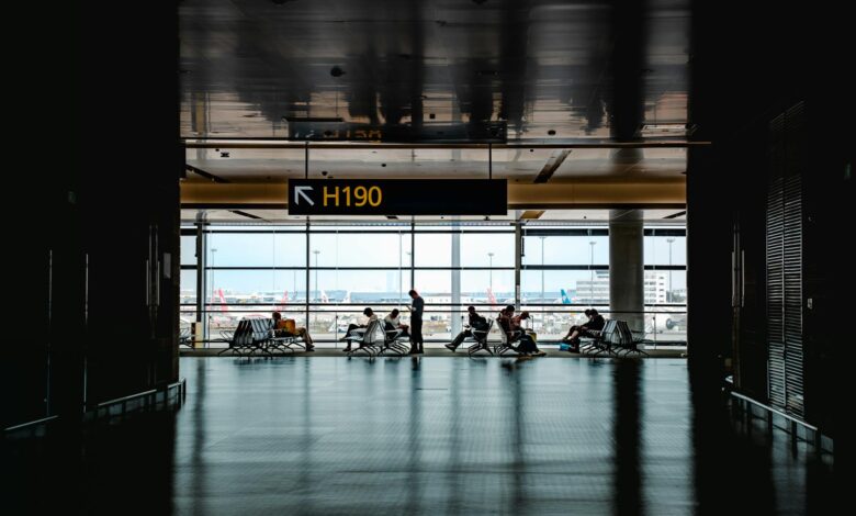 Travelers walking through busy airport terminal with luggage and departure boards