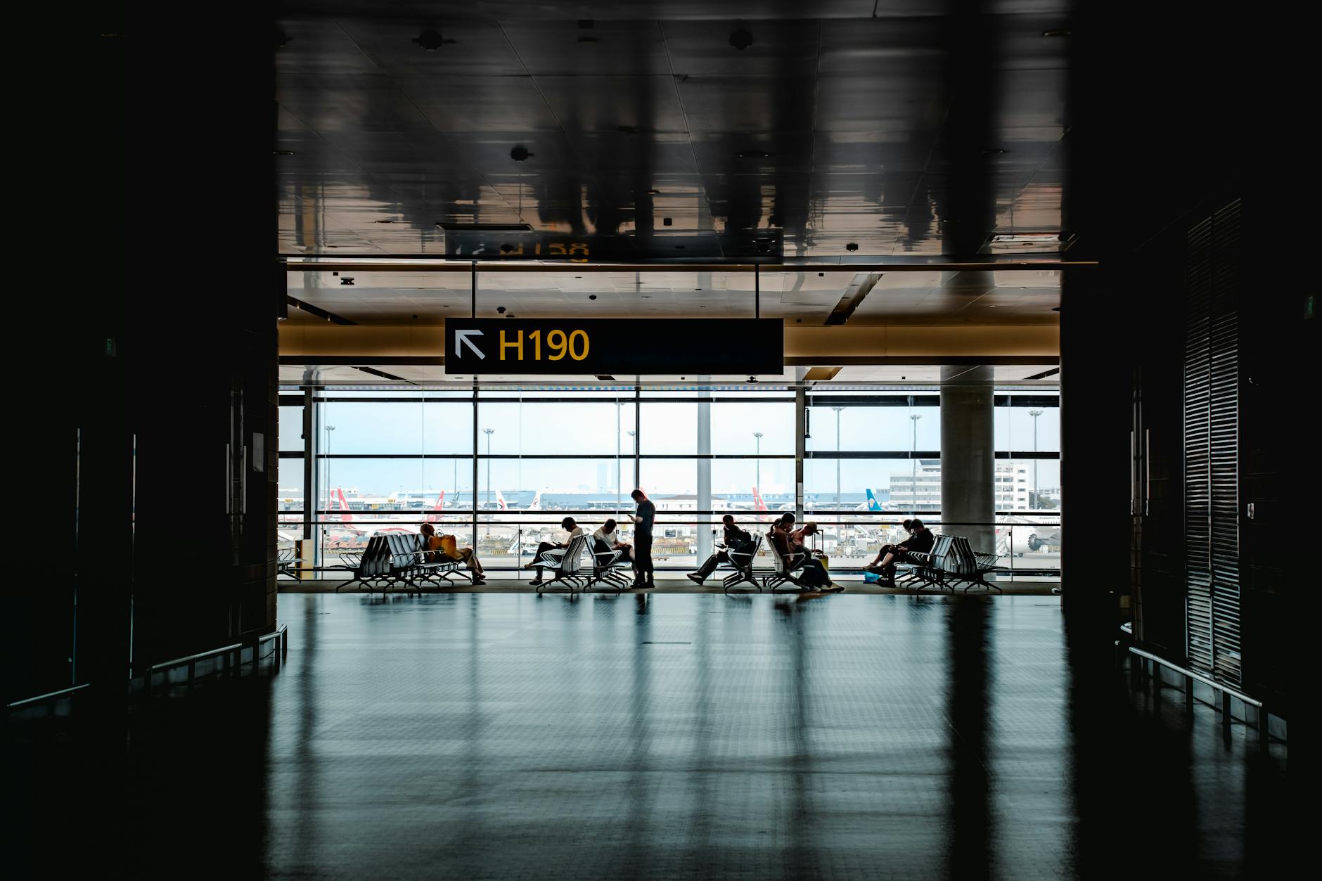 Travelers walking through busy airport terminal with luggage and departure boards