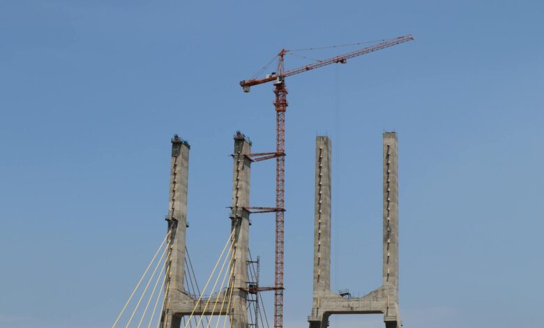 Construction workers on a bridge infrastructure project with cranes and steel beams