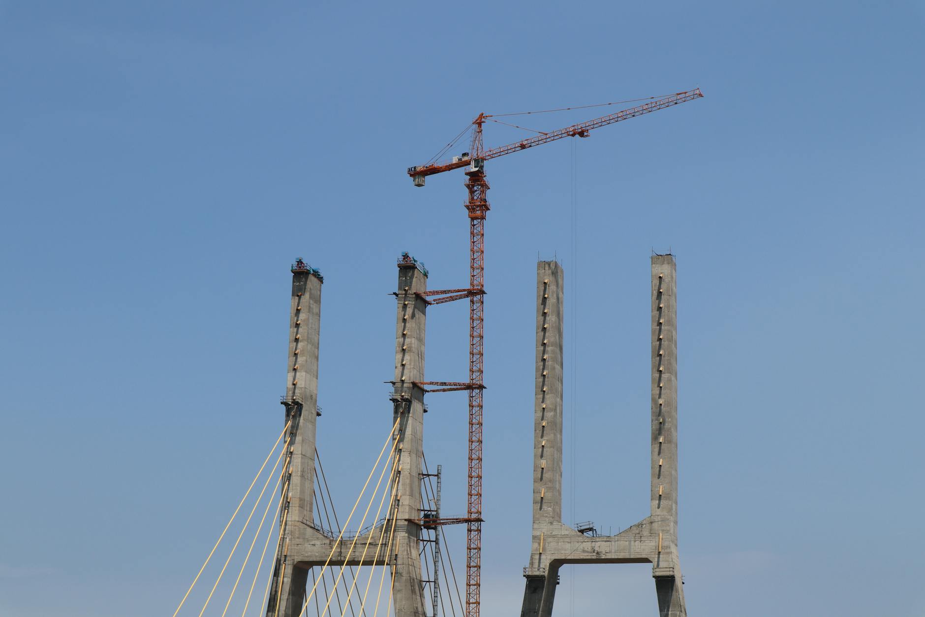 Construction workers on a bridge infrastructure project with cranes and steel beams