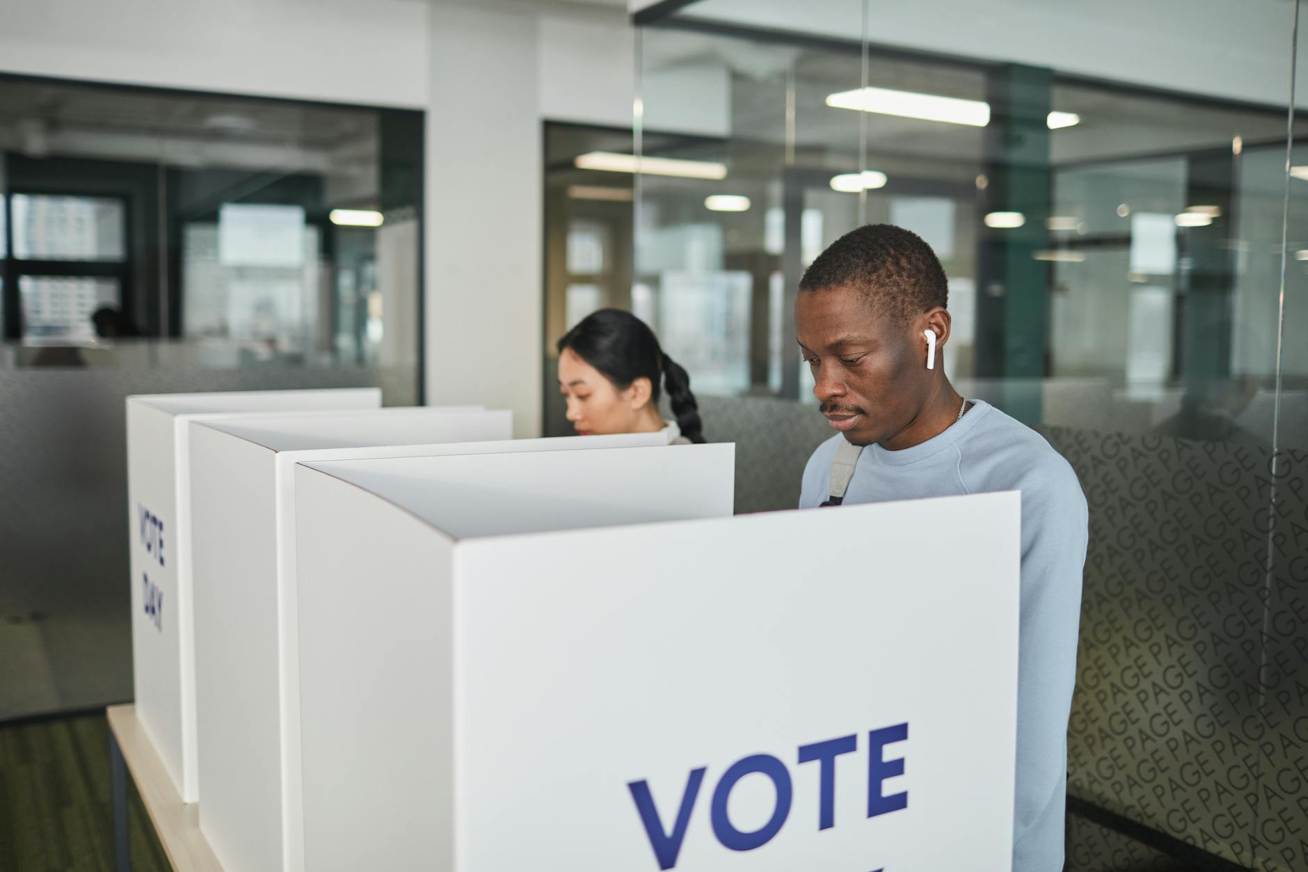 Person marking ballot in voting booth with privacy screen