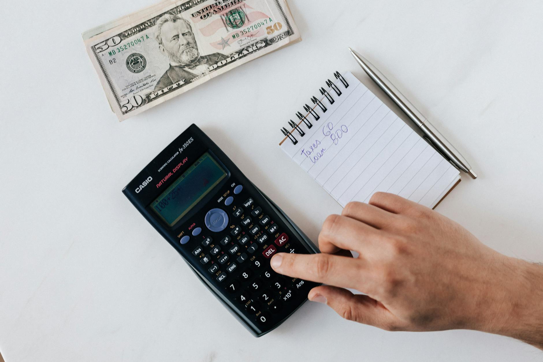 Financial calculator next to cash and financial documents on a desk for budget planning