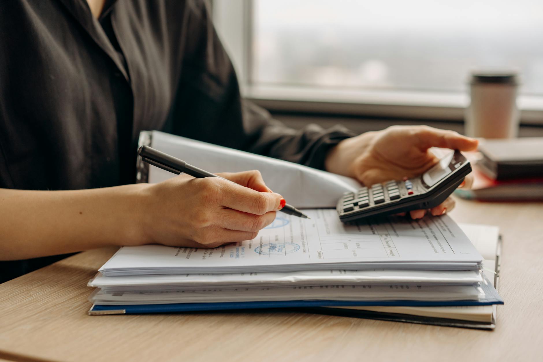 Tax documents and financial paperwork spread on desk with calculator and pen