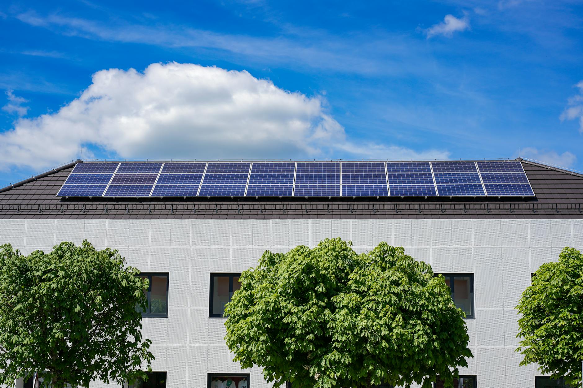 Solar panels installed on commercial building rooftop with blue sky background
