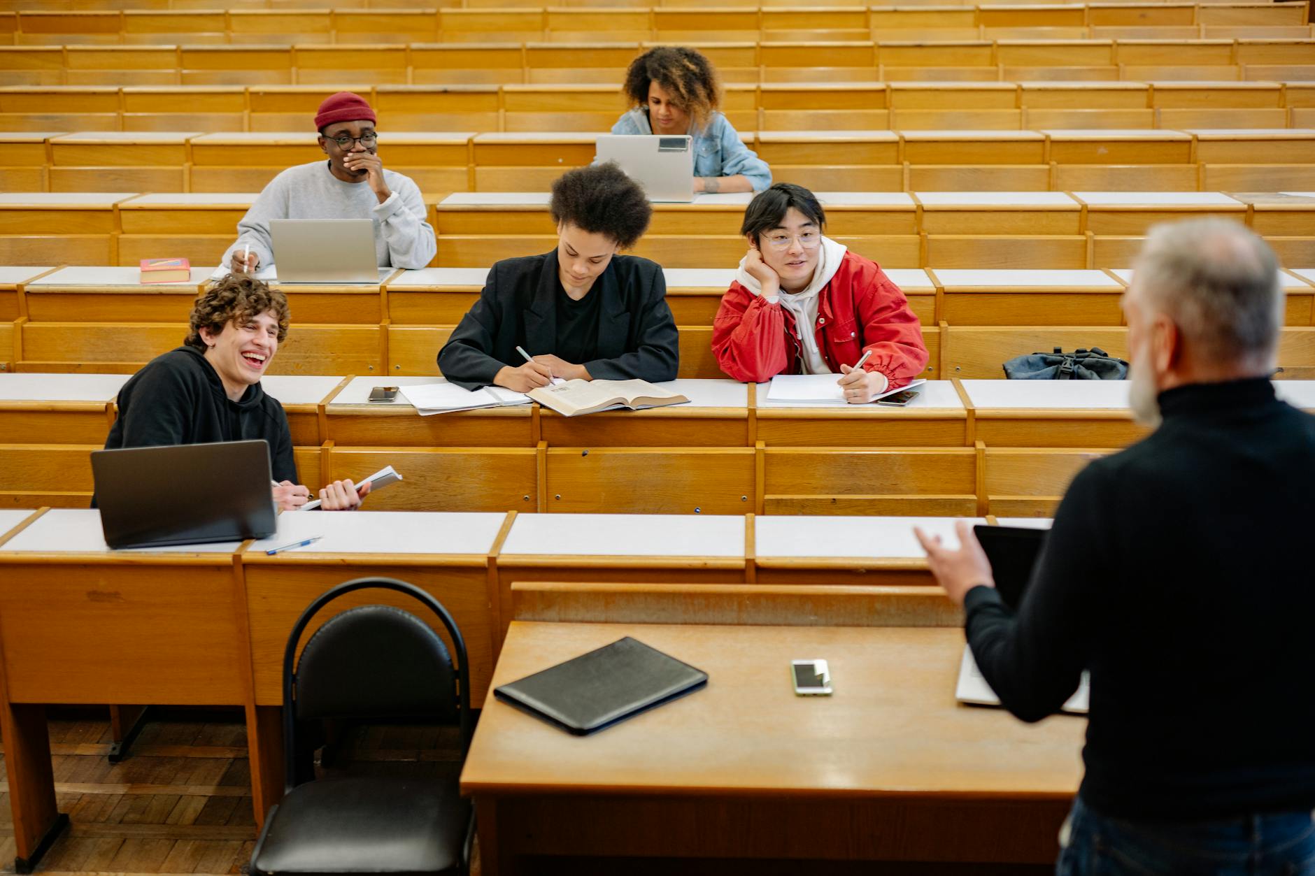 University lecture hall with students attending class and professor at podium