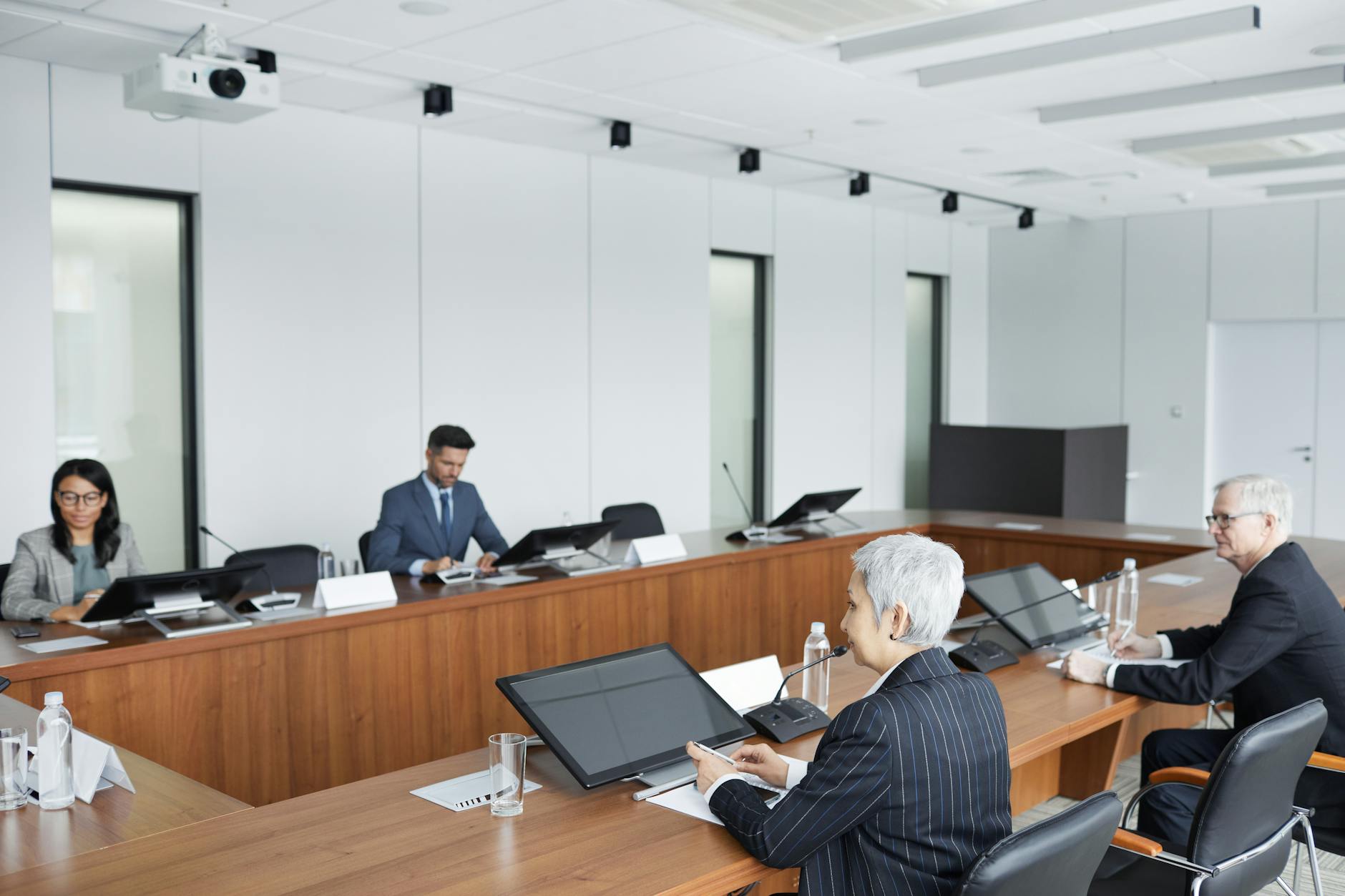 Professional business meeting in modern boardroom with people reviewing documents