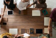 Business professionals shaking hands across a conference table during loan negotiation meeting
