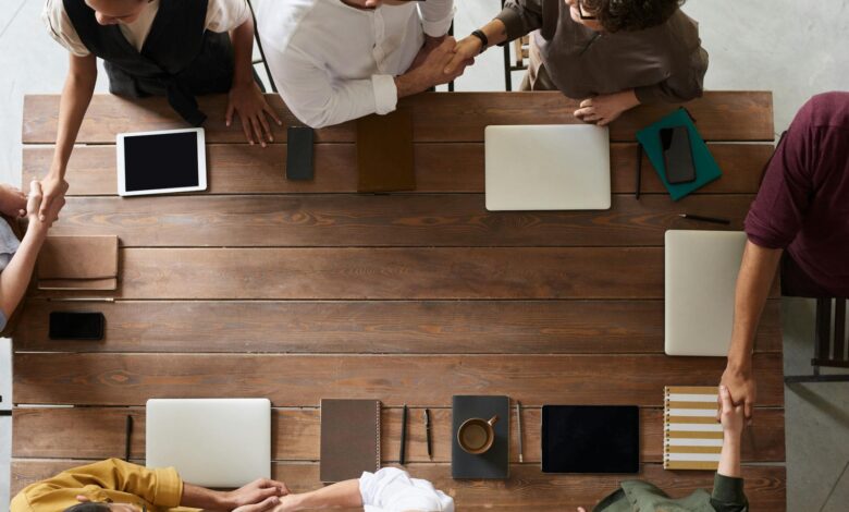 Business professionals shaking hands across a conference table during loan negotiation meeting