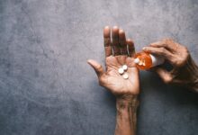 Senior person holding prescription medication bottle while reading pharmacy information