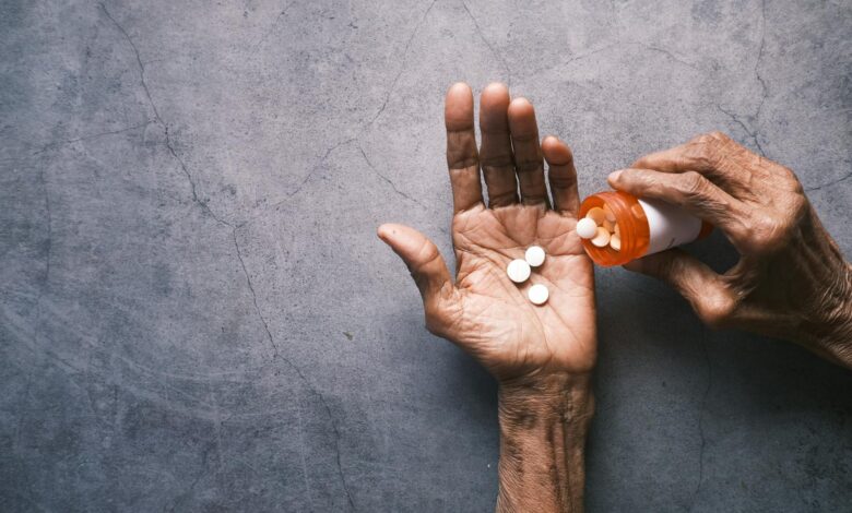 Senior person holding prescription medication bottle while reading pharmacy information