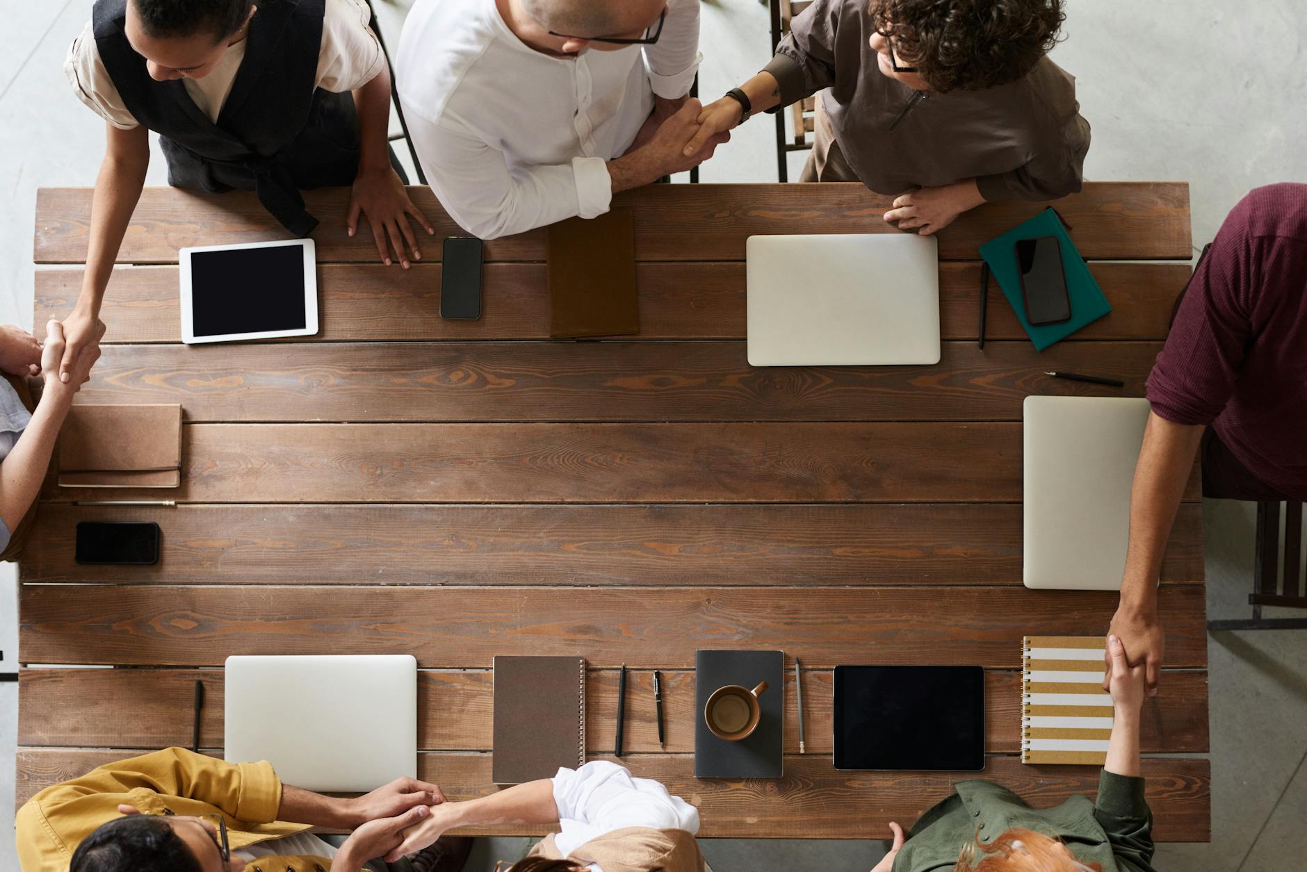 Business professionals shaking hands across a conference table during loan negotiation meeting