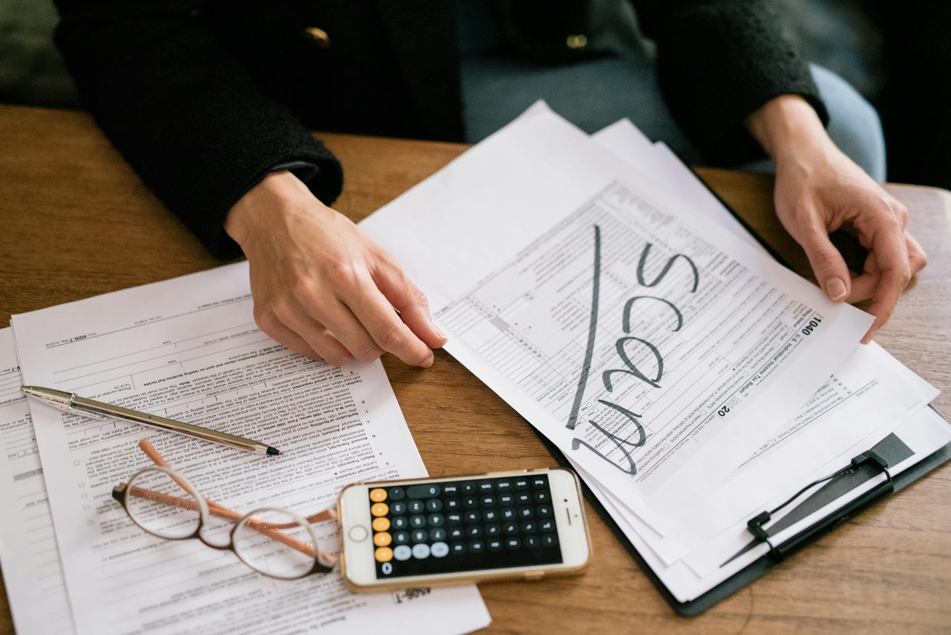 Person reviewing tax forms and financial paperwork at a desk