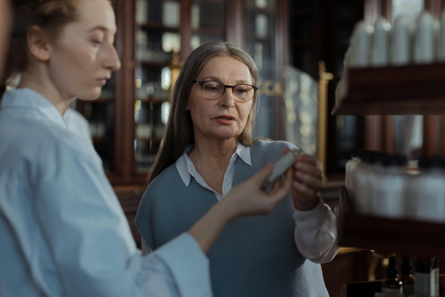Pharmacist consulting with elderly patient at pharmacy counter about medications