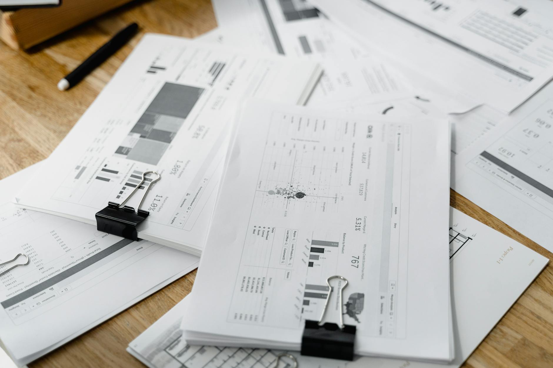 Stack of financial documents and loan papers on desk with calculator and pen