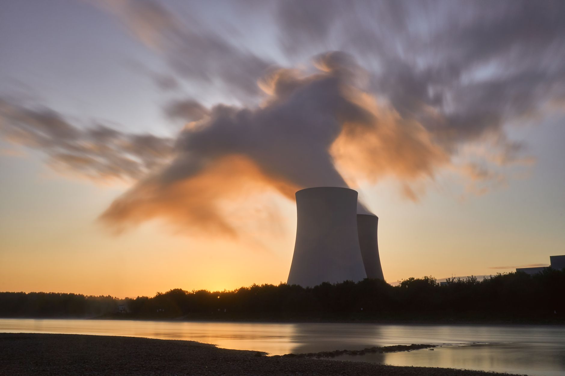 Aerial view of a nuclear power plant with cooling towers beside a river