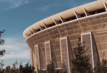 Exterior view of a large sports arena at dusk with illuminated signage