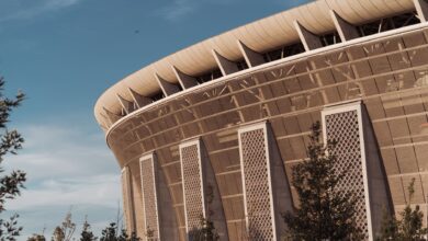 Exterior view of a large sports arena at dusk with illuminated signage