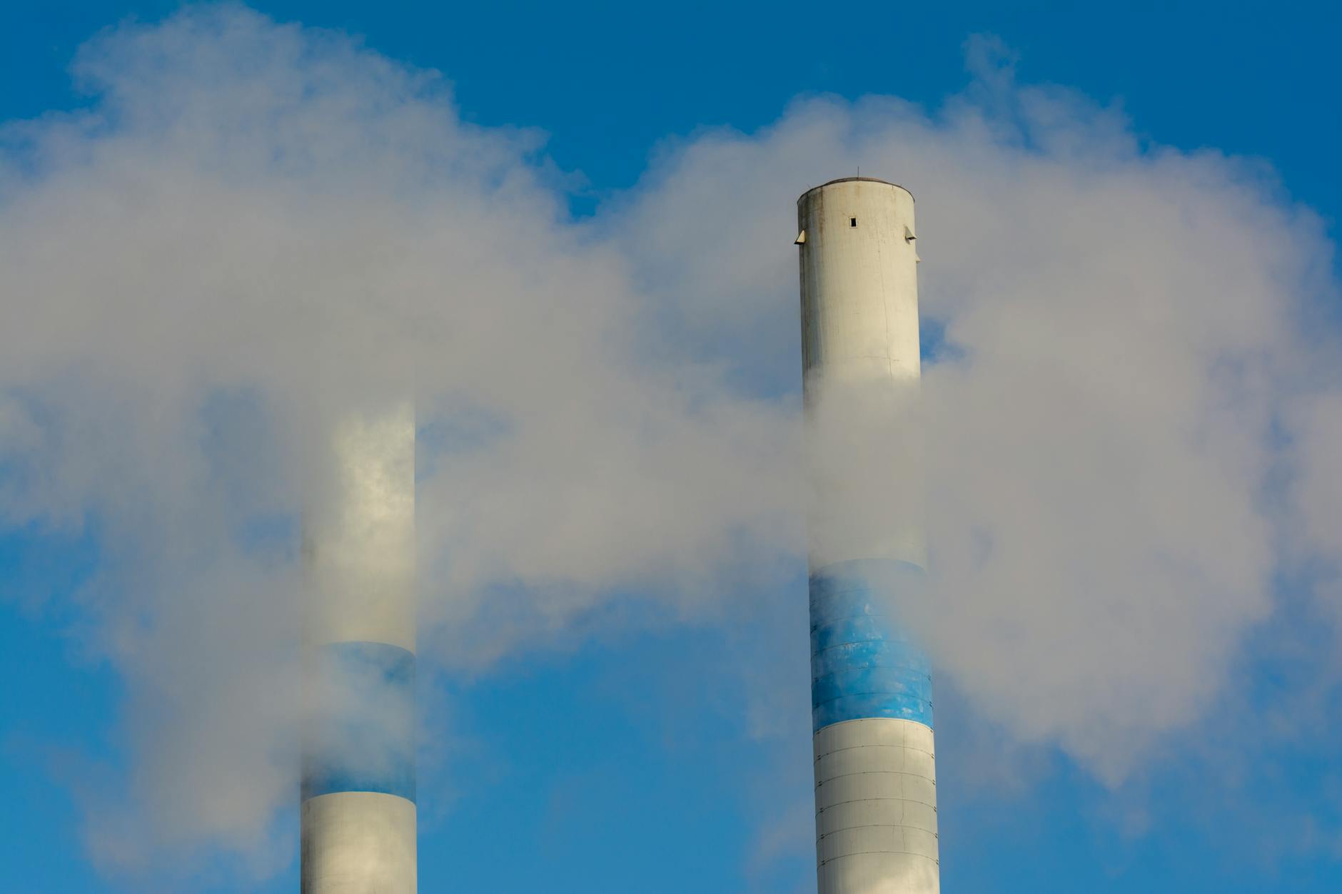 Industrial smokestacks releasing emissions against a grey sky