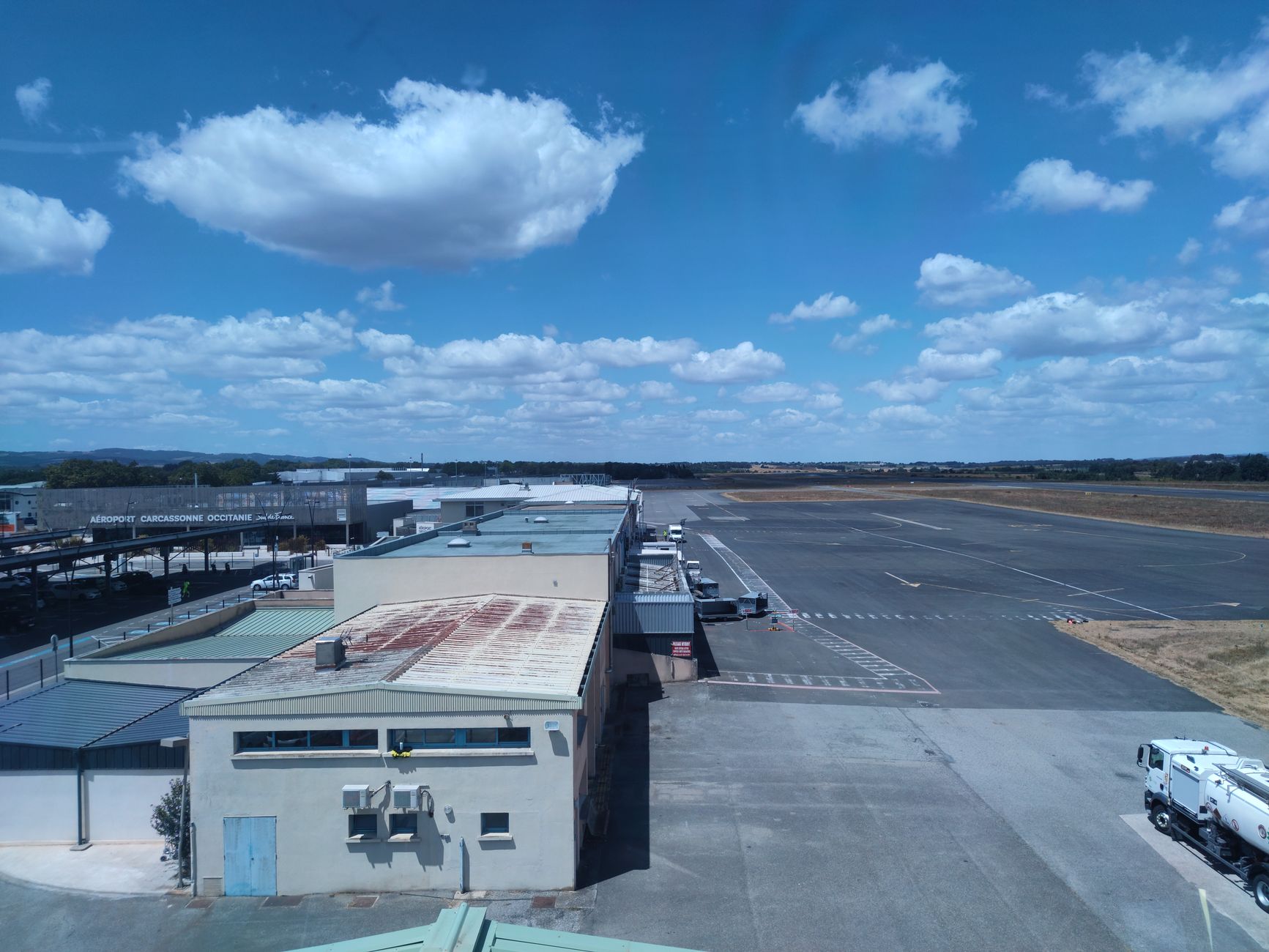 Quiet regional airport terminal exterior with limited passenger traffic