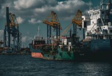 Large cargo ship docked at a commercial shipping port with stacked containers