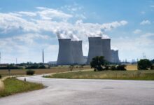 Aerial view of a nuclear power plant with cooling towers reflecting in a river