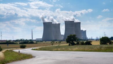 Aerial view of a nuclear power plant with cooling towers reflecting in a river