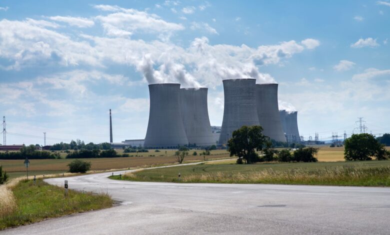 Aerial view of a nuclear power plant with cooling towers reflecting in a river