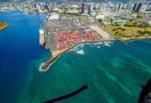 Aerial view of a busy maritime cargo port with container ships and loading cranes
