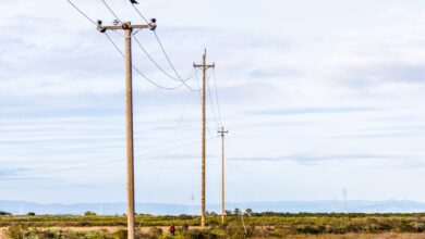 High-voltage electricity transmission lines crossing rural farmland at sunset