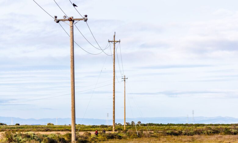 High-voltage electricity transmission lines crossing rural farmland at sunset