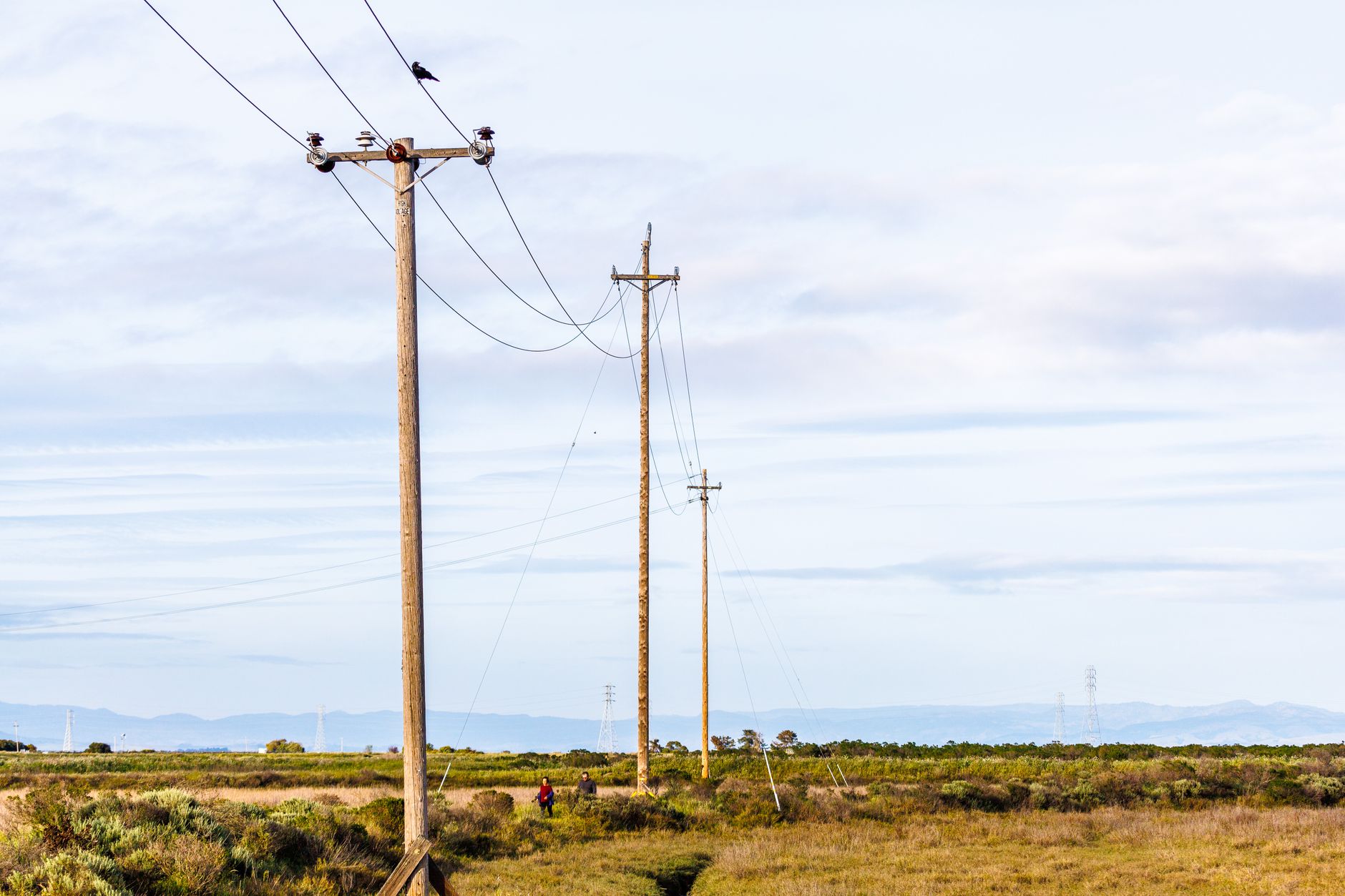 High-voltage electricity transmission lines crossing rural farmland at sunset