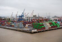 Shipping containers stacked at a busy commercial port terminal