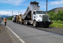 Road construction workers laying fresh liquid asphalt on a highway surface