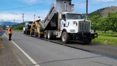 Road construction workers laying fresh liquid asphalt on a highway surface