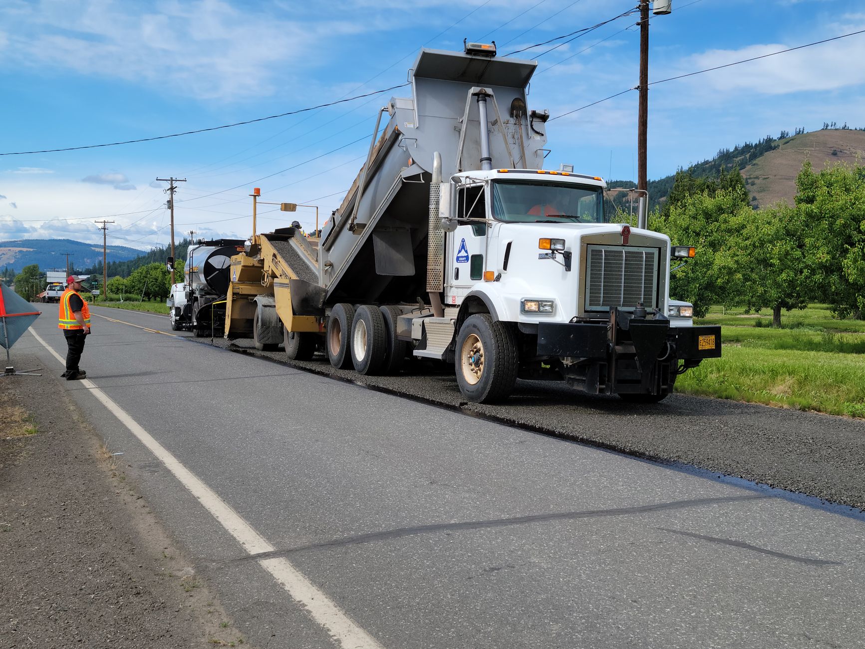 Road construction workers laying fresh liquid asphalt on a highway surface