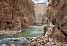 Large hydropower dam with water flowing through spillways in a mountain river valley